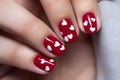 Clos eup of woman\'s Valentine\'s day fingernails with red colored nail polish with white hearts