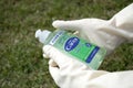 Close angle of a person`s hands wearing beige colored gloves holding the `carex` antibacterial gel.