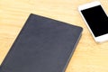 Close black blank notebook and mobile on wooden table,Mock up for adding your content
