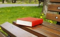 Close book in the red cover lies on a park bench Royalty Free Stock Photo