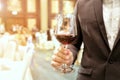 Close of of business man wearing suit holding a glass of wine in the company party with ray yellow light in the background.