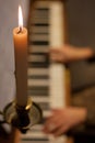close candle on a candlestick. against the background of a girl playing the piano. romantic atmosphere.