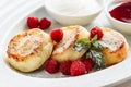 Close cheese pancakes, syrniki, curd fritters with fresh raspberries on white plate background