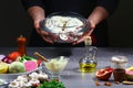 Close the chef`s hands. Raw fresh rabbit meat with sour cream, rosemary leaves and garlic in a glass pot ready to be cooked