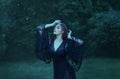 Close eyes, girl dancing in the moon light in the dark emerald forest alone. magic. witch. demon. wearing a black long Royalty Free Stock Photo