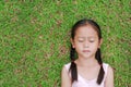 Close eyes little Asian child girl with two ponytail hair lying on green grass in the garden Royalty Free Stock Photo