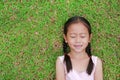 Close eyes little Asian child girl with two ponytail hair lying on green grass in the garden Royalty Free Stock Photo