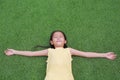 Close eyes little Asian child girl with two ponytail hair lying on green grass in the garden Royalty Free Stock Photo