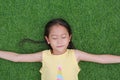 Close eyes little Asian child girl with two ponytail hair lying on green grass in the garden Royalty Free Stock Photo
