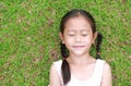 Close eyes little Asian child girl with two ponytail hair lying on green grass in the garden Royalty Free Stock Photo