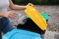 Close of female throwing out in recycling bin clean empty plastic container. Different colour of recycling bins