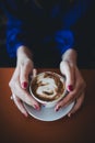 Close focus picture of lady woman hands holding tender hot cup of coffe on wooden table with silver ring on finger and red fancy m Royalty Free Stock Photo