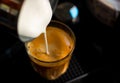 Close focus on pouring steam milk into shot of hot espresso coffee on glass cup Royalty Free Stock Photo