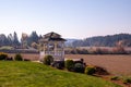 Close of a gazebo standing on a side of a lawn with in a farming fields in background