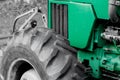 Close on a green tractor where you can see the hood, engine and large tractor tires.