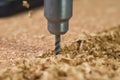 close image of drilling into corkboard, cork pieces visible