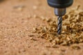 close image of drilling into corkboard, cork pieces visible