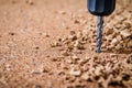 close image of drilling into corkboard, cork pieces visible