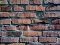 A close-up shot of a rough brick masonry wall lined with red clumsy brick for creativity, textures and background.