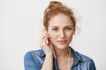 Close-ip portrait of kind gorgeous young redhead girl with blue eyes, wearing earphones while listening music or talking Royalty Free Stock Photo