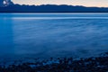 Close long exposure shot of evening sea, pebble coast and mountain silhouette of Olympic park in Picnic Point area