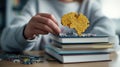 Close medium shot of a student assembling a brainshaped puzzle atop an academic book stack highlighting the connection Royalty Free Stock Photo