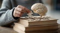 Close medium shot of a student assembling a brainshaped puzzle atop an academic book stack highlighting the connection Royalty Free Stock Photo
