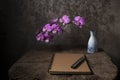 close note book and purple orchid in vase on an old wooden tabl