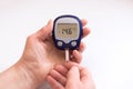 Close person checking blood sugar with glucometer and test strip at home