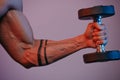 Close photo of muscular arm which is doing bicep curls under blu Royalty Free Stock Photo
