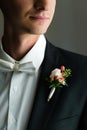 Close picture of a neat broom`s shoulder in a fine wedding suit with a nice bunch of flowers
