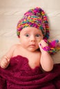 Close portrait of adorable baby in knitted funny gnome hat lies on his back