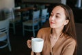 Close portrait of an attractive beautiful girl holding and drinking a cup of coffee in her hand and smiling Royalty Free Stock Photo