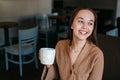 Close portrait of an attractive beautiful girl holding and drinking a cup of coffee in her hand and smiling Royalty Free Stock Photo