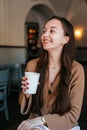 Close portrait of an attractive beautiful girl holding and drinking a cup of coffee in her hand and smiling Royalty Free Stock Photo