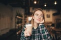 Close portrait of a beautiful girl holding a cup of coffee in her hand, looking into the camera and smiling. Positive student girl Royalty Free Stock Photo