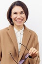 close portrait of a beautiful, happy woman in a brown coat with glasses in her hand, smiling cutely at the camera while Royalty Free Stock Photo