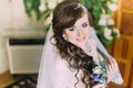 Close portrait of beautiful smiling bride with long curly hair posing in wedding dress at interior Royalty Free Stock Photo