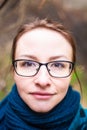 Close portrait of beautiful young smiling woman in glasses ang blue scarf looking at the camera. Blonde girl with brown eyes Royalty Free Stock Photo