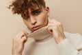 a close portrait of a handsome, attractive man with curly hair, in a light turtleneck pulled over his face, pulling it Royalty Free Stock Photo