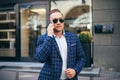 Close portrait a man. stylish young guy talking on the phone wearing a blue jacket white shirt and sunglasses. busy Royalty Free Stock Photo