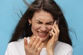 a close portrait of a sad, depressed woman with her hair blowing in the wind during a telephone conversation. Horizontal