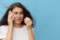 a close portrait of a sad, depressed woman with her hair blowing in the wind during a telephone conversation. Horizontal