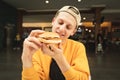 Close portrait of a satisfied boy with a burger in his hand, hungry looking at a sandwich and wants to eat it, background of a