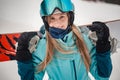Close portrait of smiling woman wearing stylish blue outfit while holding her snowboard Royalty Free Stock Photo
