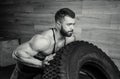 A bodybuilder with a tattoo and beard is pushing a tire in a gym