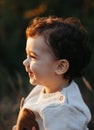 Close portrait of a sweet smiling toddler baby boy in autumn park on sunset. Curly hair boy Royalty Free Stock Photo