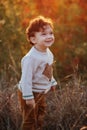 Close portrait of a sweet smiling toddler baby boy in autumn park on sunset. Curly hair boy Royalty Free Stock Photo