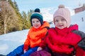 Close portrait of two happy kids boy, girl sit in snow smiling Royalty Free Stock Photo