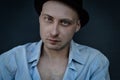 Close portrait of a young bald man with blue eyes and a black hat looking intently at the camera Royalty Free Stock Photo